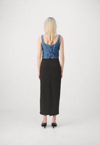 Denim crop top koos musta ribakanga maxi kleidiga, millel on vöökoht ja pehme tekstuur, mida täiendavad terava ninaga mustad kontsakingad.