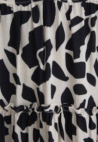 Schwarzes und cremefarbenes, gestuftes Kleid mit einem abstrakten Tierdruck, strukturiertem Stoff und einem Rüschensaum mit dezentem Glanz.