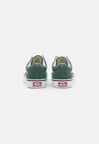 Grønne semskede lavsko med hvite gummisåler og svarte accenter. Har polstret krage og Vans-logo på hælen.