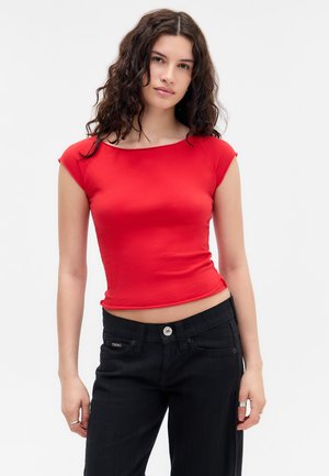 Camiseta roja ajustada con mangas de capucha, que presenta un escote redondo. Combinada con pantalones negros texturizados, que muestran un detalle de botón en la cintura.