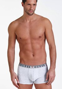 Szürke pamut boxer alsónadrág fekete derékkal, amelyen a "GUESS" logó található. A dizájn testhez simuló és sima textúrájú.