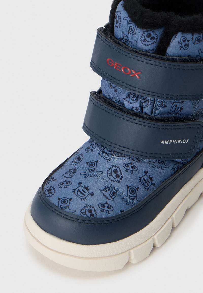 Niebieski wodoodporny but z teksturowaną cholewką z nadrukami z kreskówkowymi potworami, wzmocnionym czubkiem oraz podwójnymi rzepami dla pewnego dopasowania.