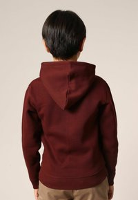 Sweat à capuche bordeaux avec une texture lisse. Comprend une poche kangourou et des poignets et un ourlet côtelés, conçu pour une coupe décontractée.
