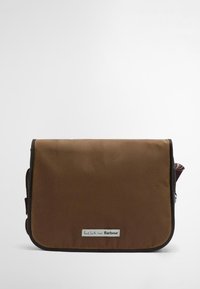 Καφέ ορθογώνιο σακίδιο όλης της ημέρας φτιαγμένο από ανθεκτικό ύφασμα. Διαθέτει κλείσιμο με καπάκι, λογότυπο και πολύχρωμο ριγέ ύφασμα που φαίνεται στην άκρη.