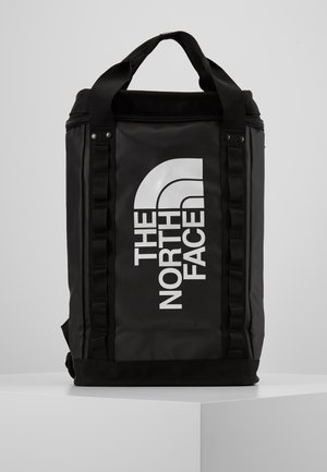 Czarny prostokątny plecak z górnymi uchwytami, pionowymi paskami i dużym białym logo "THE NORTH FACE" na przednim panelu.