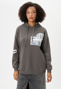 Grijze hoodie met een grote grafische print op de voorkant, met een mix van texturen; ribgebreide manchetten en zoom, met een zijsplit.