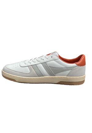 La sneaker présente une tige en cuir blanc avec des accents en daim gris, un talon rouge, une semelle texturée, cinq œillets et une zone de pointe perforée.