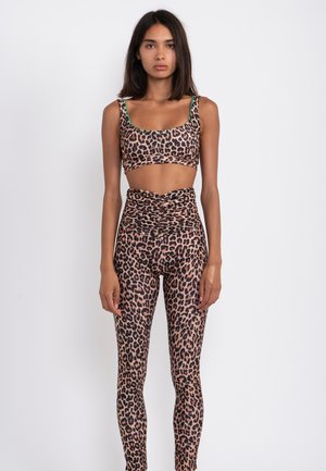 Leopard print crop top and high-waisted leggings, made from stretchy fabric. Features green accents on straps. Smooth texture.