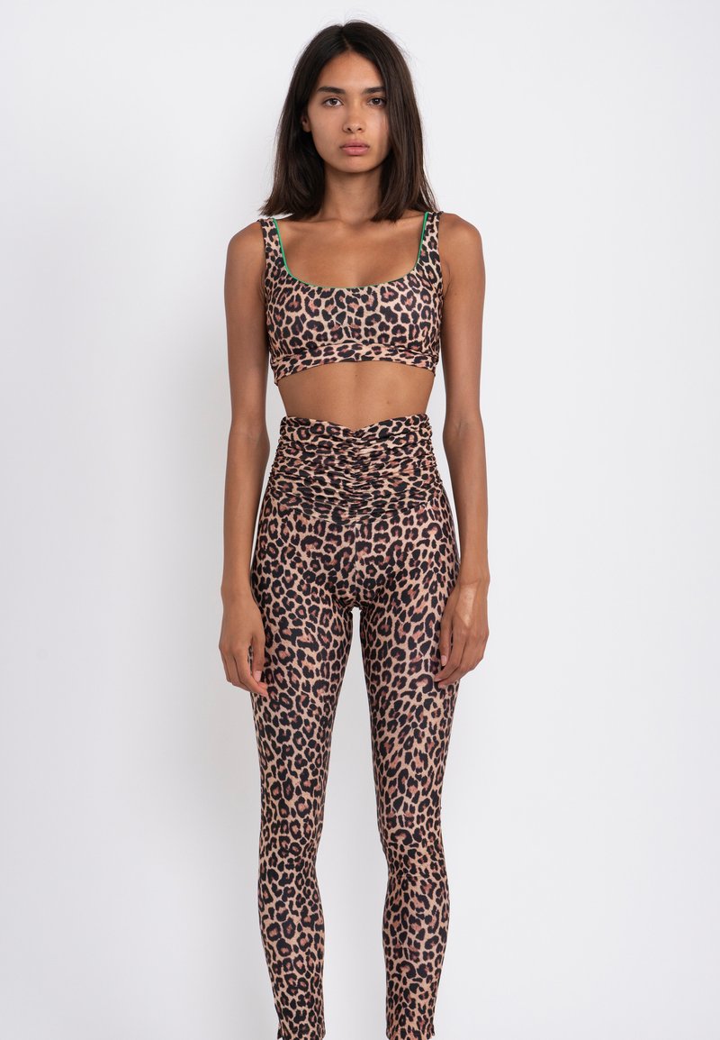 Top corto con stampa leopardata e leggings a vita alta, realizzati in tessuto elastico. Presenta dettagli verdi sulle bretelle. Texture liscia.