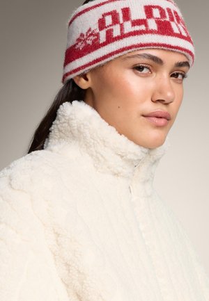 Fuzzy cream fleece jacket with a high collar, featuring a textured design and a zip closure. White and red striped knit headband with "ALPS" text.