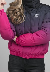 Padded bunda s ombre designem od černé po růžovou. Má vysoký límec, elastické manžety a malé vyšívané logo na hrudi.