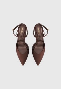 Barna, hegyes orrú sarkú cipők sima selyemfényű kialakítással, slingback pánttal és arany csattal, valamint párnázott béléssel.