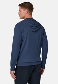 Sweat-shirt à capuche bleu marine avec manches longues, poignets côtelés et une finition texturée subtile ; vue de dos montrant une coupe décontractée et un design simple.
