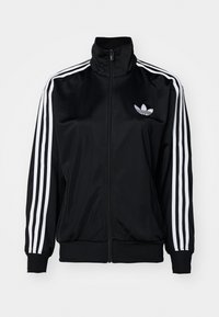 Chaqueta de chándal negra con cremallera y cuello alto. Presenta tres franjas blancas en cada manga y un pequeño logo blanco en el pecho.