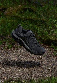 Chaussure de trail running noire avec un dessus texturé, un capuchon renforcé et un système de laçage. Design léger, adapté aux terrains extérieurs.