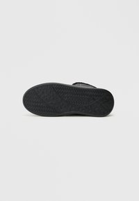 Μαύρη σόλα παπουτσιού με υφή που διαθέτει γεωμετρικά σχήματα και το λογότυπο "VALENTINO" ανάγλυφο. Λείος τελείωμα στις άκρες.