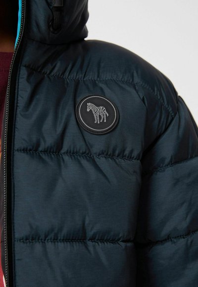 Jūras spēku pufferkakls ar quilted dizainu, melnu apļu uzlīmi ar zebras motīvu un pielāgojamu kapuci. Mīksta tekstūra un gluda apdare.