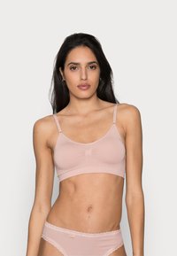 Bralette rosa claro com alças finas, tecido suave e detalhe central drapeado. Acompanhado de um par de calcinhas com rendas combinando.