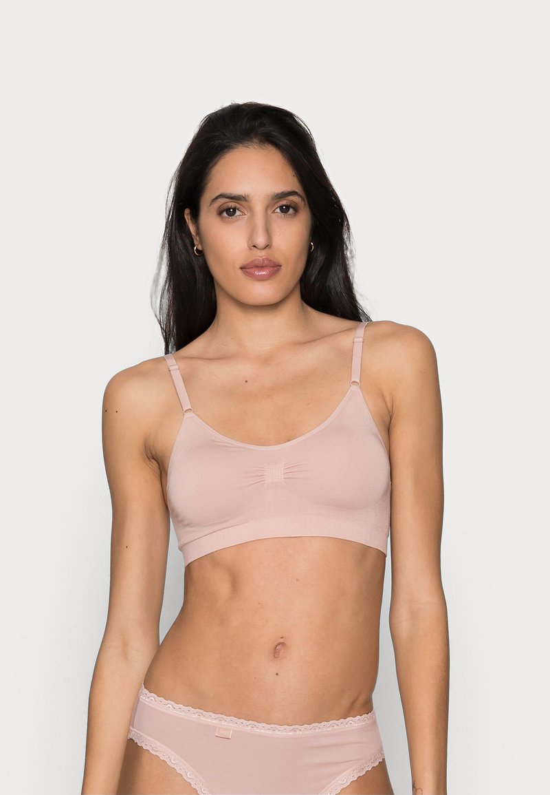 Bralette rosa claro com alças finas, tecido suave e detalhe central drapeado. Acompanhado de um par de calcinhas com rendas combinando.