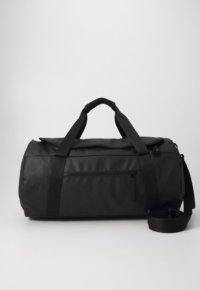 Sac de sport noir avec une texture lisse et mate. Comprend deux poignées supérieures, une bandoulière détachable et une poche avant zippée.