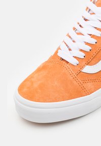 Baskets en daim orange avec lacets blancs et semelle en caoutchouc. Présente des détails cousus et un accent logo blanc sur le côté.