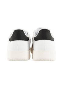 Baskets blanches avec des accents noirs au niveau du talon, en matière synthétique lisse, avec un bout arrondi et une semelle en caoutchouc texturée. La vue arrière montre un design minimaliste.