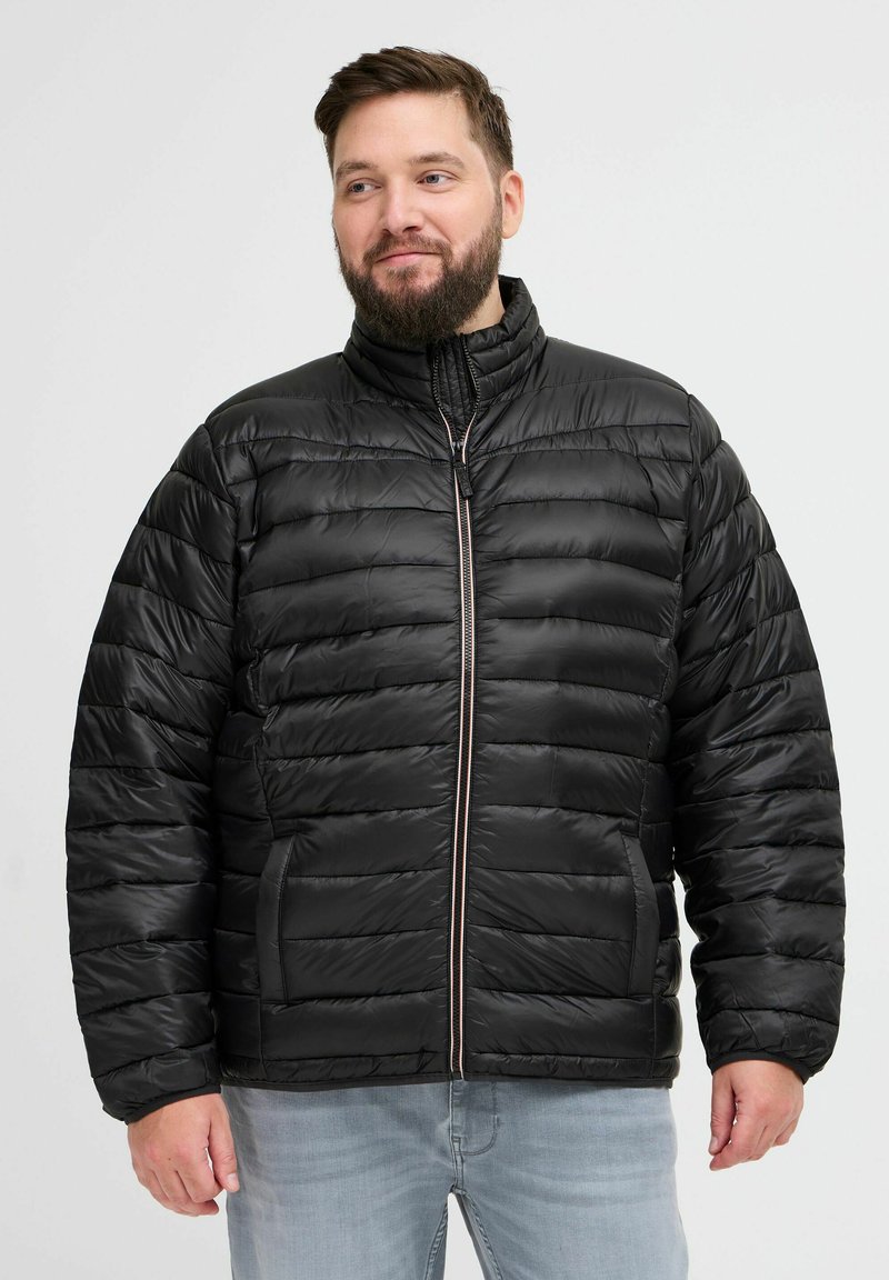 Chaqueta acolchada negra con diseño de acolchado horizontal, cuello alto y cremallera frontal. Presenta bolsillos laterales y una textura suave y brillante.