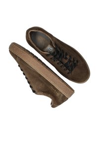 Braune Wildleder-Sneaker mit strukturiertem Obermaterial, schwarzen Schnürsenkeln und einer kontrastierenden hellbraunen Gummisohle mit einzigartigem Profilmuster und Logo.