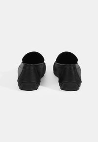Schwarze Lederschuhe mit glatter Textur, abgerundeten Fersen und einer soliden Gummisohle mit strukturiertem Profil. Minimalistisches Design.