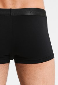 Boxer in cotone neri realizzati in un tessuto elasticizzato con una vita liscia. Il design presenta un aspetto minimalista senza motivi o dettagli visibili.