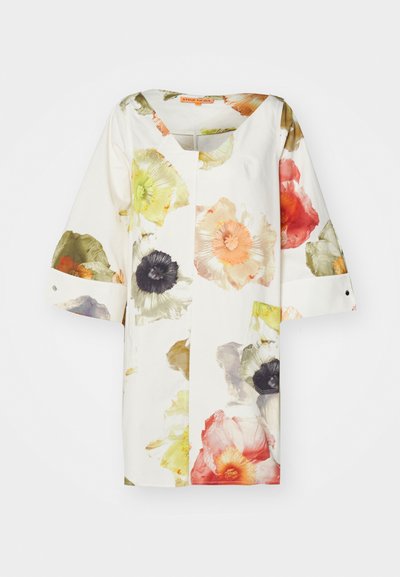 Túnica floral de manga corta. Presenta un fondo blanco, flores vibrantes en naranja, rosa, verde y negro. Silueta amplia, escote redondo.