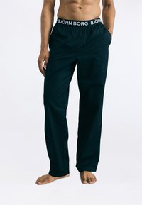 Fekete, laza szabású nadrág könnyű anyagból, kontrasztos fehér derékkal, amelyen a "BJÖRN BORG" logó található, valamint oldals�ó zsebekkel.