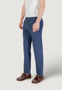 Chinos blu navy in cotone con design a gamba dritta, dotati di chiusura frontale con bottone e tasche laterali, indossati con scarpe da barca marroni.