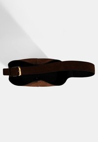 Braune Wildleder-Schultertasche mit einem breiten Riemen, ausgestattet mit einer goldenen Schnalle und einem offenen Innenraum, der das minimalistische Design betont.