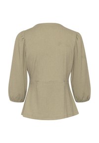 Top peplum beige con maniche a palloncino, tessuto strutturato, scollatura rotonda e dettaglio arricciato in vita per una vestibilità definita.