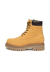Gelbe Leder-Stiefeletten mit einem braunen Kragen, ausgestattet mit Metallösen, Schnürsenkeln und einer groben, strukturierten Sohle. Weiches Innenfutter sichtbar.