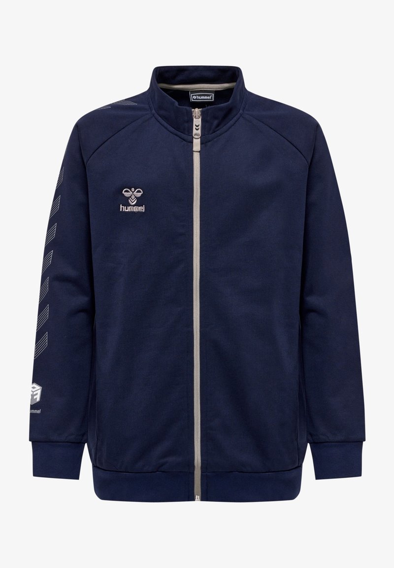Veste zippée bleue marine fabriquée à partir d'un tissu lisse, avec un col montant, des accents blancs et un logo sur la poitrine et la manche.