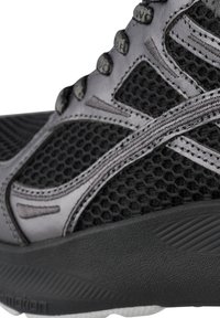 Black athletic shoe featuring a mesh upper with a honeycomb texture, sleek overlays, and a thick sole for cushioning.