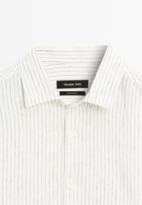 Chemise à col blanc avec de fines rayures verticales bleues et deux boutons visibles, étiquetée Massimo Dutti, fabriquée en Égypte.