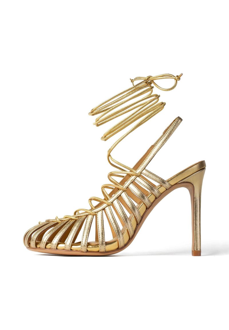 Sandalie aurii cu toc înalt, cu un design cu curele, având curele subțiri din metal și un toc stiletto subțire. Textură netedă și reflectorizantă.