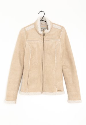 Veste polaire beige à fermeture éclair avec bordure en laine blanche sur le col, les poignets et l'ourlet, suspendue à un cintre noir sur fond blanc.