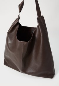 Hnědá kožená kabelka přes rameno s texturovaným povrchem, širokým otevíráním, jedním popruhem a minimalistickým designem.