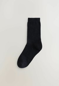 Čierna ponožka vyrobená z mäkkej tkaniny, má rebrovaný lem a hladkú textúru, s klasickým dizajnom a zaoblenou špičkou.