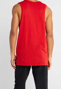 Rød ærmeløs tanktop lavet af letvægtsstof, med en afslappet pasform, sideslidser og en rund halsudskæring.