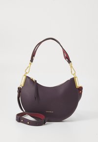 Purple leather handbag with a curved shape, gold hardware, detachable strap, and textured surface. Logo displayed on the front.