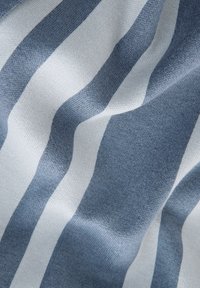 Venytetty kangas, jossa on teksturoitu pinta ja vaihtoehtoiset leveät raidat vaaleansinisinä ja valkoisina, esittelee pehmeän, kudotun ilmeen.