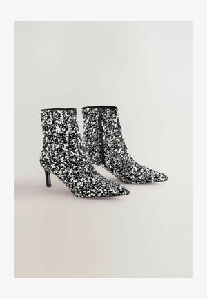 Bottines noires en sequins avec des bouts pointus, des talons stilettos et une fermeture éclair. Caractéristiques d'une surface texturée grâce aux sequins et d'un intérieur lisse.