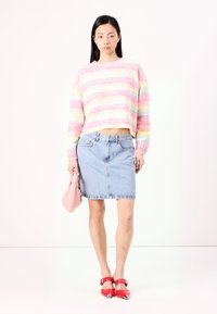 Gehaakte trui met pastelstrepen, lichte denimrok, rode hoge hakken en een roze clutch. Smooth texturen en levendige kleuren.