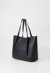 Sac fourre-tout en cuir noir avec une finition texturée, doté de deux poignées, d'un design à ouverture supérieure et d'une forme minimaliste.