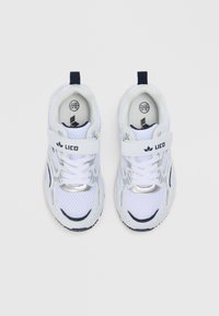 Λευκά αθλητικά παπούτσια από πλέγμα με ασημί λεπτομέρειες, μπλε στοιχεία και ταινία Velcro. Διαθέτουν στρογγυλή μύτη και υφή σόλας για καλύτερη πρόσφυση.